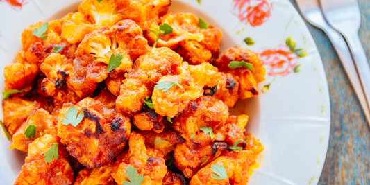 A plate of golden, crispy baked buffalo cauliflower bites garnished with fresh parsley.