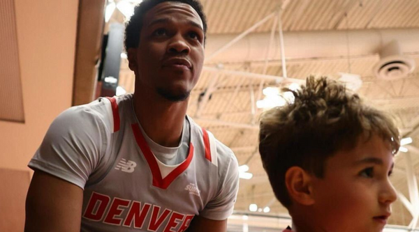 Tommy Bruner, a guard for the Denver Pioneers, looking upwards during a game. He is wearing a white and red Denver jersey with the number 0.